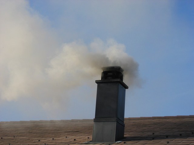 Rauchender Kamin auf Hausdach